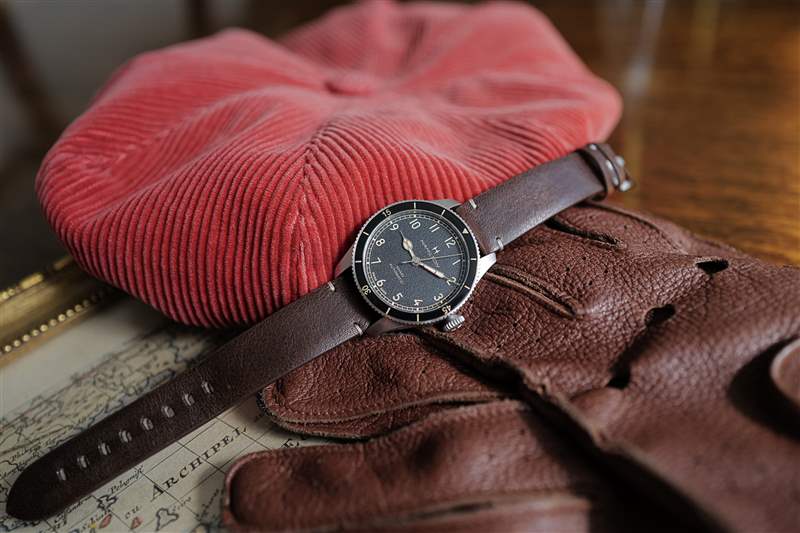 38 毫米尺寸的 Hamilton Khaki Pilot Pioneer 戴紅色帽子，戴著駕駛手套。