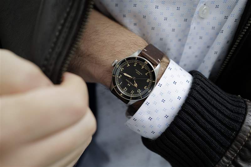 38 毫米尺寸的 Hamilton Khaki Pilot Pioneer 戴在手腕上，手伸進(jìn)棕色皮夾克的口袋里。